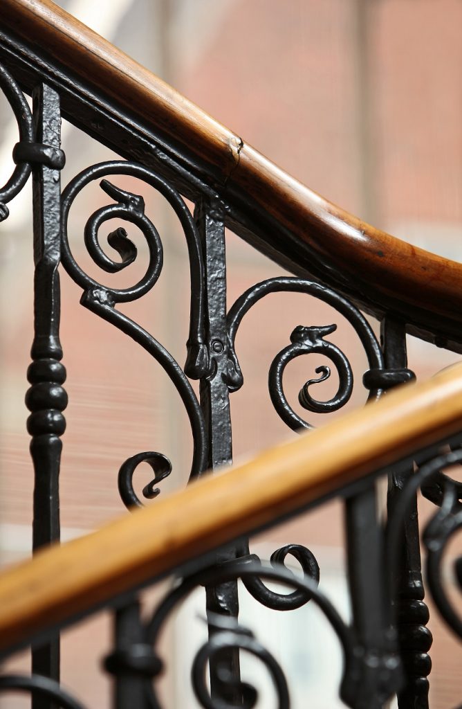 close up of iron stair railing with wooden beam